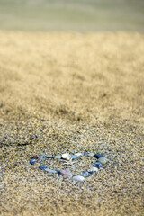 Fototapeta na wymiar Hart on sand made from rocks and shells