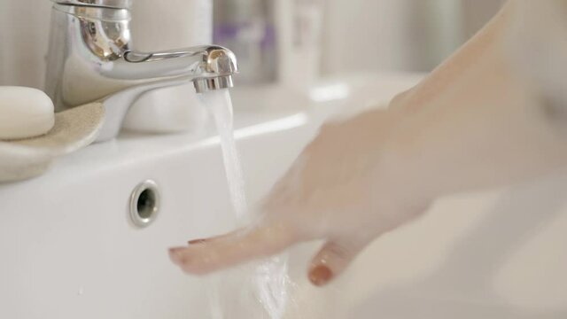 Young woman washing hands in bathroom