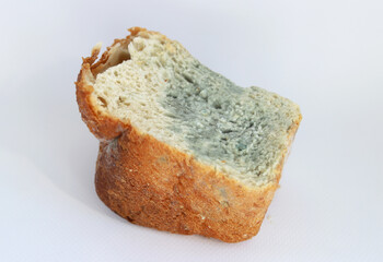 Half a loaf of white bread with mold on a white background. Selective focus. Moldy, spoiled bread.