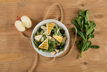 Fresh vegetable salad seasoned with oil on a wooden background