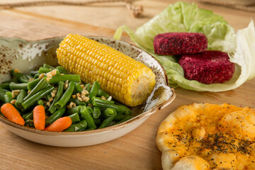 Beans and corn in a plate, next to it lies bread and beet cutlets