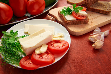 healthy food - fresh bread and feta cheese on a wooden background, tomatoes, greens and vegetables