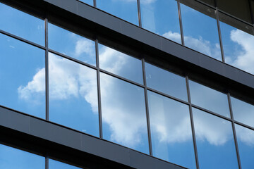 facade of a modern building on a bright Sunny day, blue sky and clouds reflecting in a glass, beautiful exterior of the new building