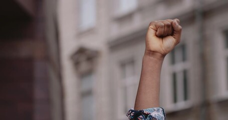 Crop view of female african american person raising up hand with clenched fist at city street. Concept of social justice and peaceful protesting racial injustice