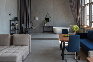 Modern minimalistic dark gray loft style studio apartment interior design. kitchen, sitting area, workplace, shower and bath. bright sun rays inside.