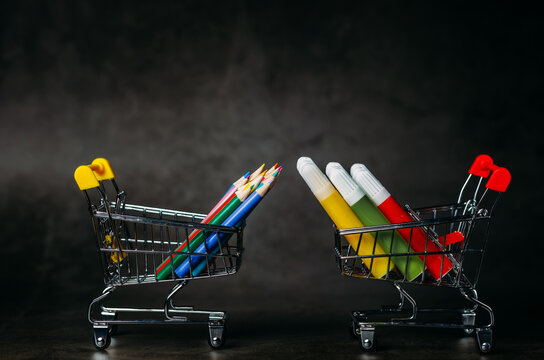 small shopping trolley, multi-colored felt-tip pens and pencils for drawing on a dark background, children's drawing set, side view, shopping for art school