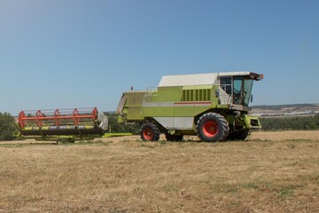green and red harvester after mowing a wheat field