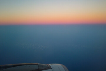 Naklejka na ściany i meble sunset over the sea in a plane
