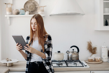 Young woman looking at tablet at home at her kitchen