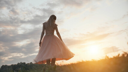 Fototapeta na wymiar The girl in the dress swirls magically at sunset.
