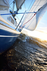 White sailboat in an open sea at sunset. Single handed sailing a 34 ft yacht. Close-up view of the...
