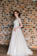 Fototapeta premium Portrait of red haired girl wearing wedding dress against a white studio background.