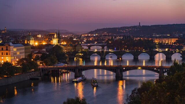 Prague, Czech Republic, timelapse view of Prague cityscape showing medieval bridges and boats on the Vltava river at dusk. 