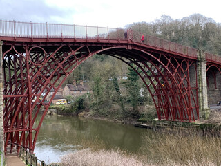 Ironbridge is a town on the River Severn, at the heart of the Ironbridge Gorge, near Telford, Shropshire, England, featuring river and bridge with surrounding terrain and houses.