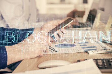 Double exposure of man's hands holding and using a phone and crypto currency blockchain theme...