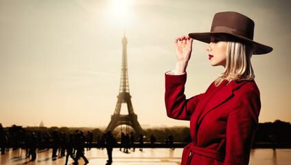 Fototapeta na wymiar girl in red coat and vintage hat with Parisian Eiffel tower on background.