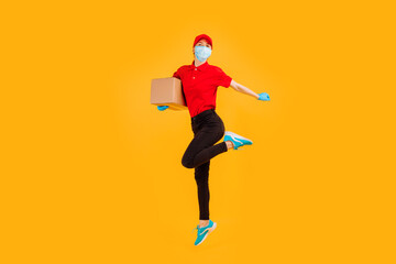 Fototapeta na wymiar A cheerful, excited, Bouncing female courier in a red Cap and t-shirt, uniform, medical protective mask and gloves, with boxes in her hands, on a yellow background. coronavirus