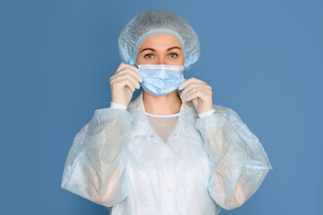 Portrait of a young woman doctor surgeon on a blue background, copy space