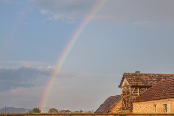 Rainbow in a field of Uljma, in the agricultural region of Banat, province of voivodina, in a field, with a barn in front, after a rain, in a half cloudy half sunny sky.