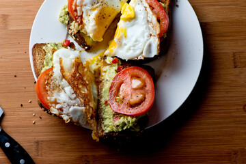 Avocado Toast. Classic American Diner Breakfast or Brunch Restaurant menu item: avocado toast. Made w/ fresh avocados smashed into guacamole and chopped tomatoes with salt and pepper served on toast.