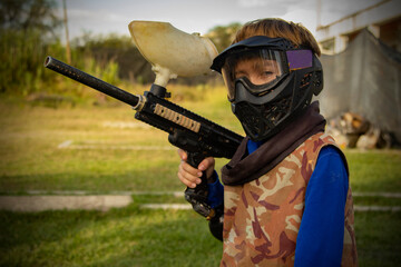 kid Gotcha player with protective mask, gun and wild attitude. Paint Bullet Players