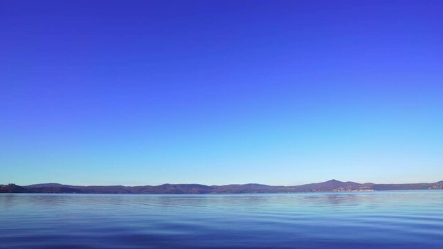 Panorama of Lake Bracciano. Blue sky and lake water. Water reservoir in Rome, Italy. Static shot. Copy space