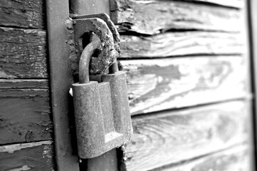 A black and white photograph of an old rusted lock sees on a wooden barn door. Prohibition concept....