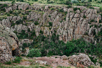Stone gray canyon among green trees, river between the mountain. One of the Wonders of the World of Ukraine is the Act of Devil's Canyon. Traveling around the country by car, climbing, climbing 