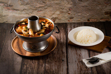 A delicious seafood soup of Thai people in a hot pot on a black background. Seafood Tom Yum with Coconut Milk