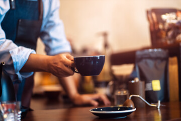 Barista serving cup of coffee on the table 