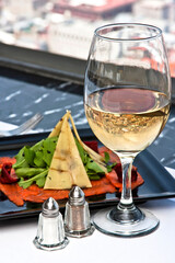 Carpaccio de salmón con queso gouda y rúcula acompañado con una copa de vino blanco