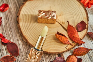A lipstick on a log against a messy background.