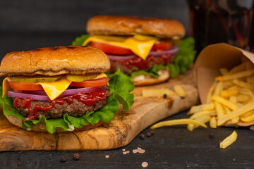 Fast and tasty food, hamburger or burger with french fries and sonova with ice on a black background with blurFast and tasty food, hamburger or burger with french fries