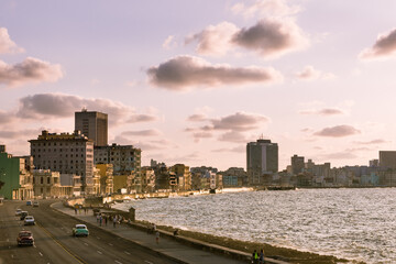 Vintage cars on the Melecon and Havana skyline at sunset