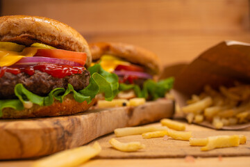 Fast and tasty food, hamburgers or burgers with french fries on a wooden table and on a wooden background
