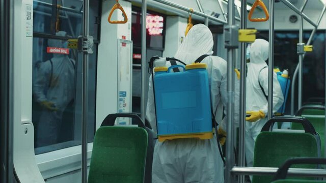 Two janitors disinfecting the tram from virus infections spraying chemicals inside. Public transport cleaning. Prevention actions. Coronavirus outbreak.