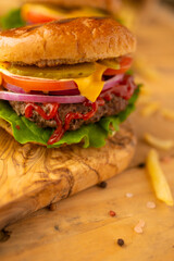 Hamburger or burger with french fries on a wooden background, tasty and unhealthy food, fast food
