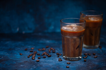 Cool cooling flight drink, iced coffee on a blue background, with coffee grains, summer mood