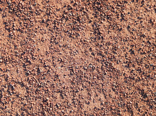 The texture of very small pebbles of brown color slightly sticking out of the cement texture, close-up.