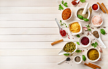 Different indian spices in a bowls and herbs on white wooden background. Top view of indian spices with copy space.