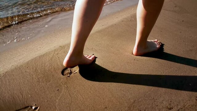 Woman walking on the beach, with waves in the background