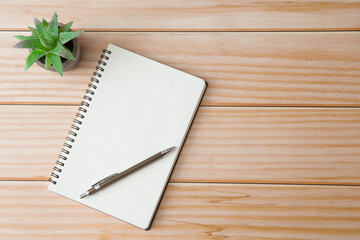 Top view of Notebooks, pens, glasses, cactus  on wooden desks with sunlight and copy space