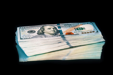 Isolated bundle of dollars. A large stack of hundred-dollar bills lies on a black background