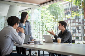 Group of young asian modern people in smart casual wear having a brainstorm meeting. Group of young asian business people discussing in the meeting.