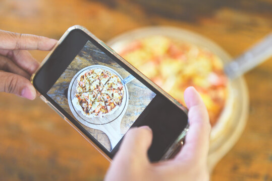 Food photography woman hands make photo Pizza with smartphone - taking photo food for post and share on social networks with camera smart phone in restaurant