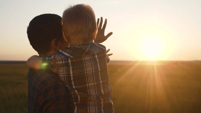 happy family father and son are pulling teamwork hands to the sun. dad and little boy cuddle stand back to sunset. happy family lifestyle parent and kid silhouette pat childhood concept