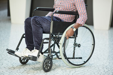 Close-up of African disabled man riding on the wheelchair along the corridor