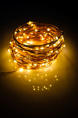 Yellow colored light chain for decoration placed on a reflective surface. Portrait view