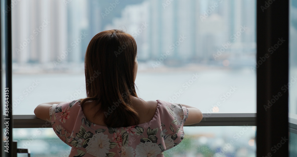 Wall mural Woman go out balcony and look around the city