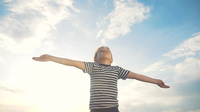 boy prays pulls hands to the sky against lifestyle a blue sky. child concept faith religion and happy family. kid son hands to the side against the blue sky jew praying to god. worship and gratitude
